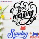 Good Morning Sunday Blessings inspirational quote with decorative typography, coffee cup icon, and fresh flowers on white wooden background